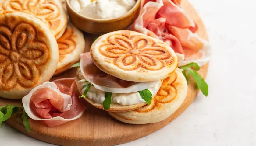 Tavola con crescentine, affettati e formaggio cremoso, un assaggio dei piatti tipici bolognesi.