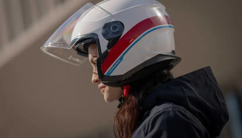Donna con casco bianco e strisce rosse e blu, un esempio di diversi tipi di casco per la sicurezza in moto.