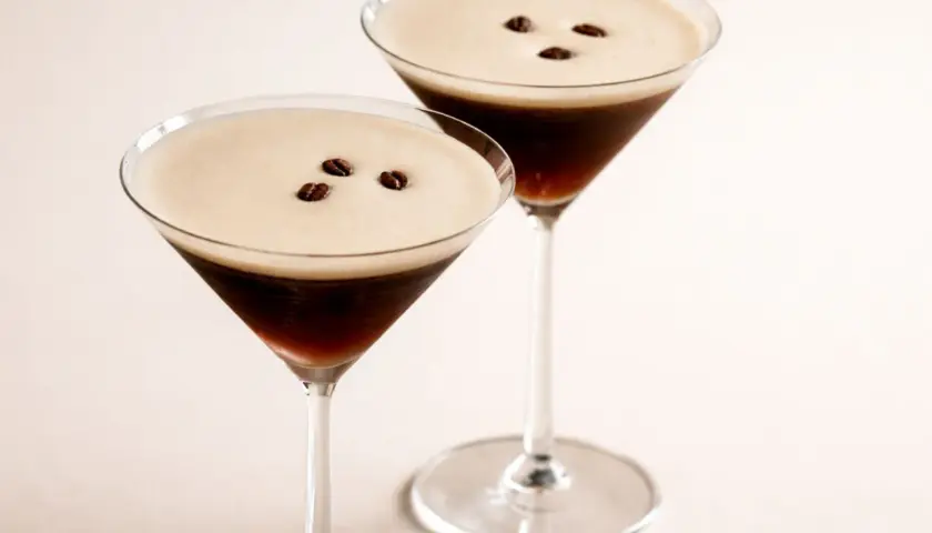 Zwei elegante Espresso Martini Gläser mit cremigem Schaum und Kaffeebohnen.