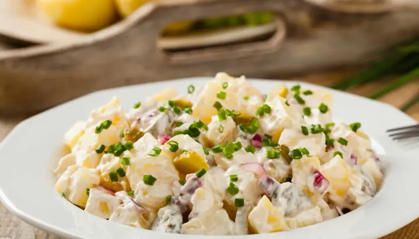 Pyszna, oryginalna kartoffelsalat z ziemniaków, ogórków kiszonych i cebuli, posypana szczypiorkiem.