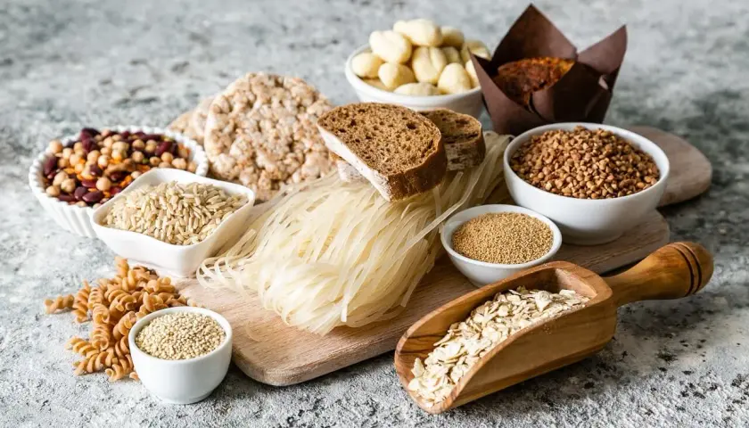 Różnorodne produkty spożywcze, w tym ryż, makaron ryżowy, kasza, płatki owsiane, chleb, ciastko i nasiona.