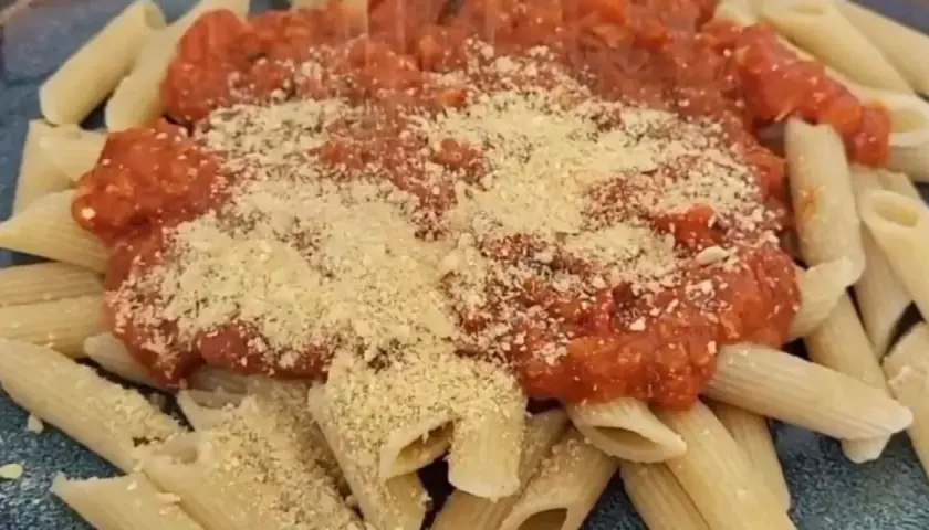 Penne mit Tomatensauce und veganem Parmesan bestreut. Ein köstliches, pflanzliches Gericht.