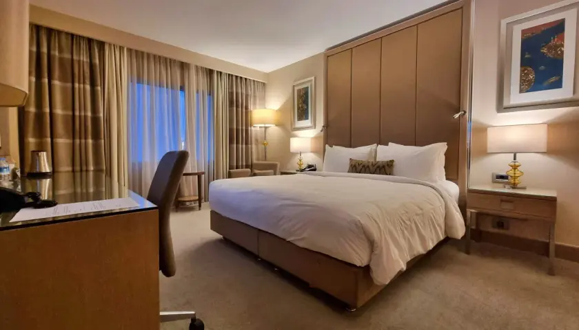 Komfortowy pokój hotelowy, idealny po długim locie tureckimi liniami lotniczymi. Duże łóżko, biurko i przytulne oświetlenie.