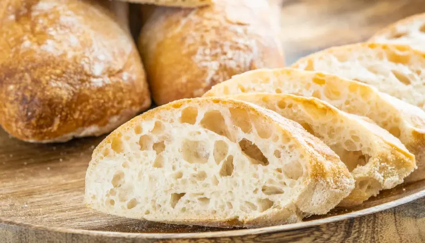 Frisch gebackene Ciabatta-Brote, aufgeschnitten auf einem Holzbrett. Dieses Ciabatta Rezept ergibt luftiges Brot mit knuspriger Kruste.