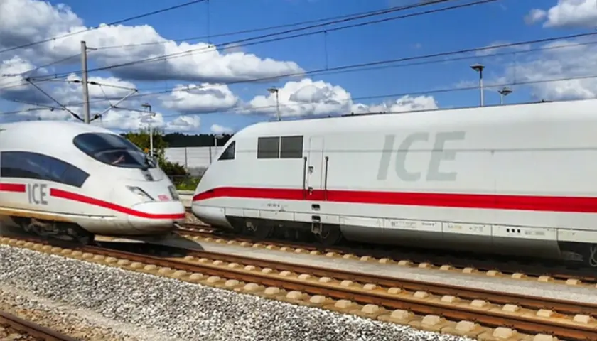 Zwei weiße ICE-Züge mit roten Streifen auf Gleisen, bereit für den Bahn Fernverkehr unter blauem Himmel mit Wolken.