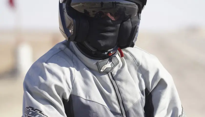 Motociclista con casco y pasamontañas, listo para viajar sin pasar frío en moto.
