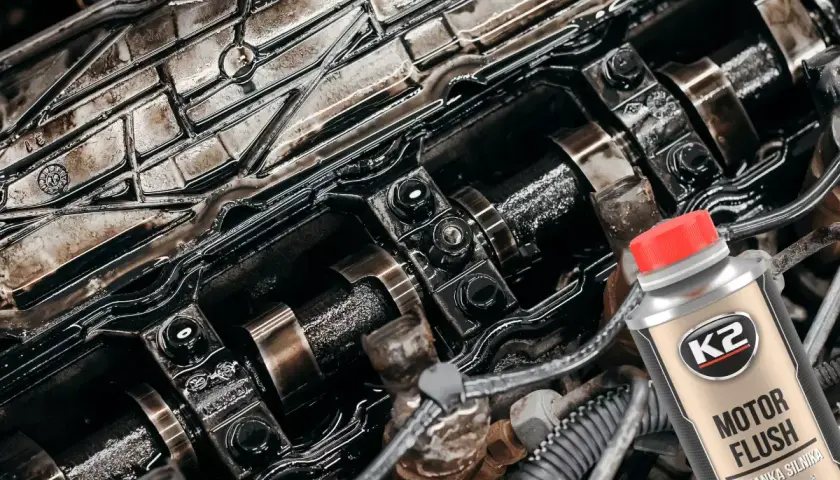 Wnętrze silnika po płukaniu ropą. Widać zabrudzone elementy i butelkę preparatu K2 Motor Flush.