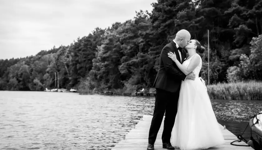 Para młoda całuje się na pomoście. Zastanawiasz się, ile kosztuje fotograf na wesele? Taka chwila warta jest uwiecznienia.
