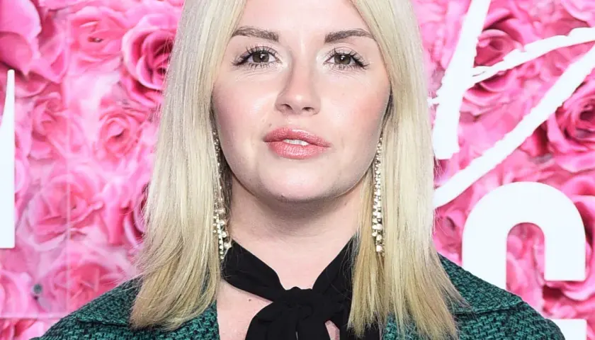 Agnieszka Wolszczyk, wiek nieznany, na tle różowych róż. Długie blond włosy, błyszczące kolczyki.