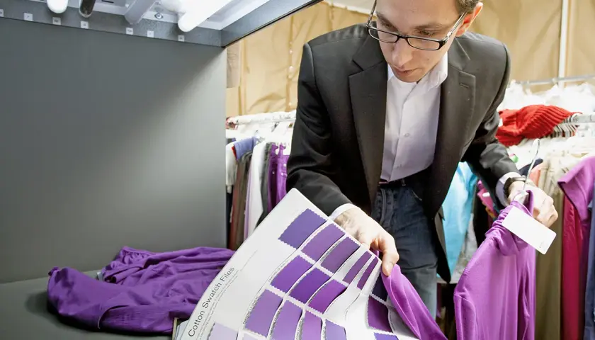 Un ingénieur textile examine des échantillons de couleurs violettes, comparant une chemise à un nuancier.