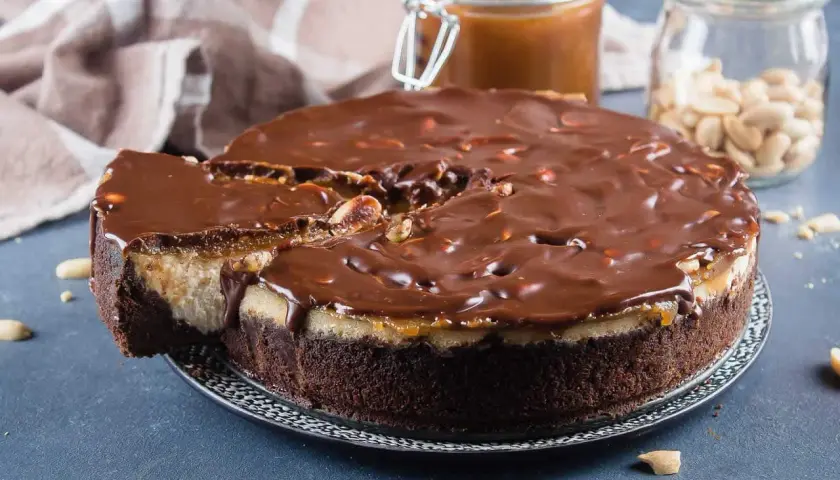 Gâteau façon Snickers, avec une base chocolatée, une couche crémeuse, du caramel coulant et une ganache au chocolat parsemée de cacahuètes. Un délice !
