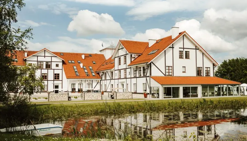Malowniczy widok na narie resort & spa z łódką przy brzegu i odbiciem w wodzie.