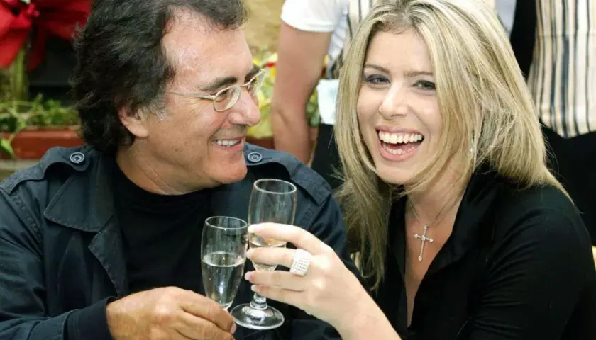 Al Bano i jego nowa partnerka, uśmiechnięci, wznoszą toasty kieliszkami szampana.