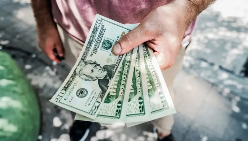 Dłoń trzyma kilka banknotów po 20 dolarów. Zastanawiasz się, skąd wziąć kasę na spełnienie marzeń?