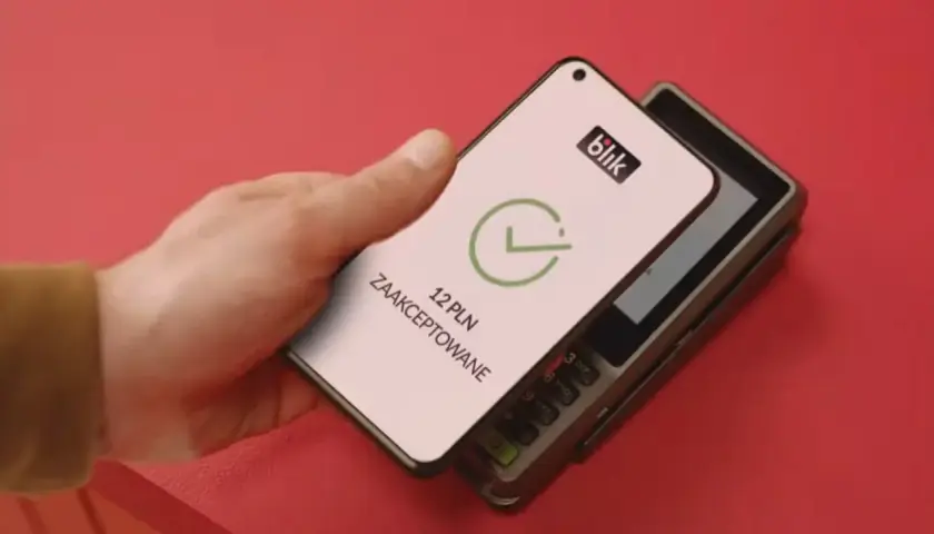 Zbliżeniowa płatność telefonem przez blik. Na ekranie telefonu widnieje potwierdzenie transakcji 12 PLN.