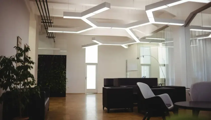 Nowoczesne biuro z designerskim oświetleniem. **LED zintegrowany co to znaczy?** To światło wbudowane w sufit, tworzące geometryczne wzory.