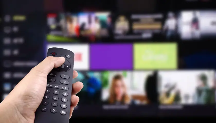 Dłoń trzyma pilot, wybierając program. Zastanawiasz się, kto jest zwolniony z abonamentu RTV? Może Ty?