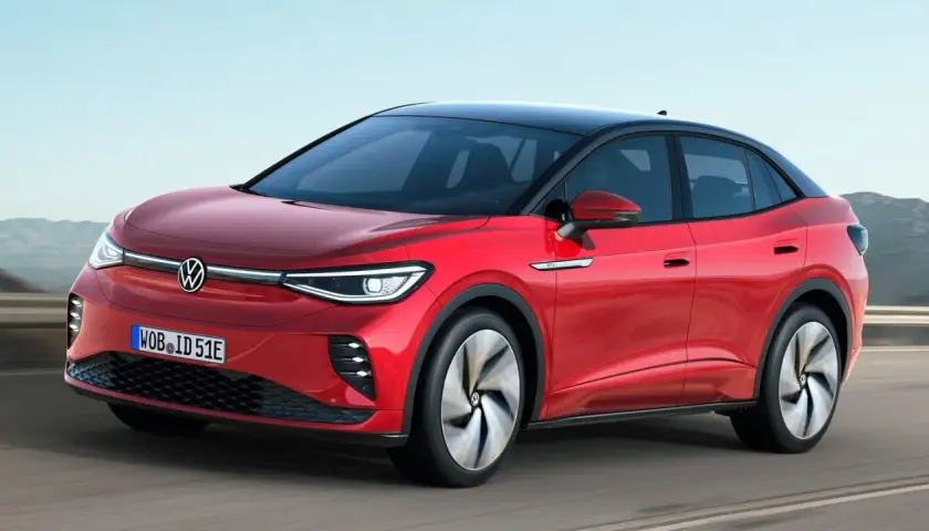 Czerwony VW ID.5 z czarnym dachem sunie po drodze, prezentując nowoczesny design i elektryczną moc.