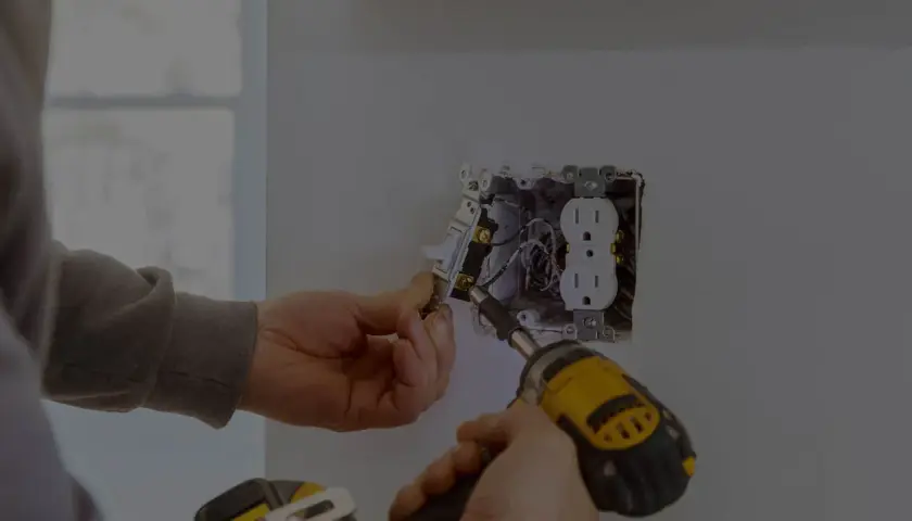 Elektryk montuje gniazdko i włącznik. Zastanawiasz się, ile kosztuje godzina pracy elektryka?