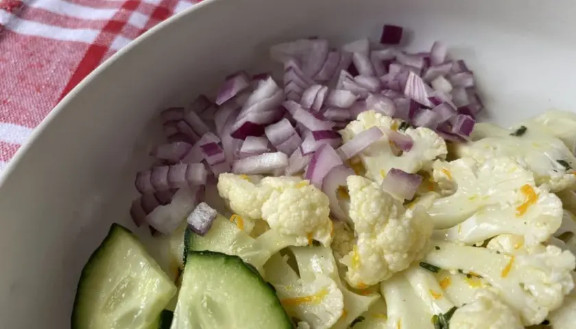 Ensalada de coliflor fresca con pepino y cebolla morada picada.