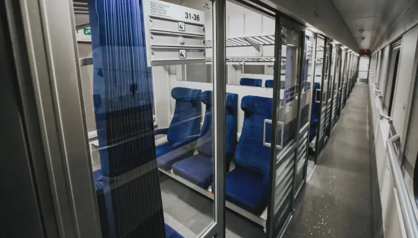 Wnętrze wagonu z przedziałami intercity 2 klasa. Puste, niebieskie siedzenia czekają na pasażerów.