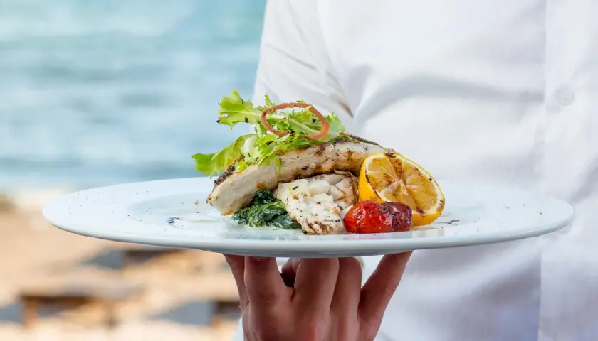 Delicioso plato de pescado a la parrilla con limón y tomate, servido en un restaurante en Cala Moraig.
