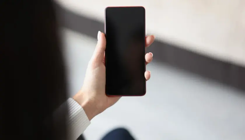 Dłoń trzyma telefon z czarnym ekranem. Czekam na powiadomienie.