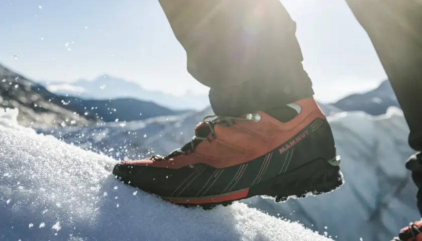 Pomarańczowe buty trekkingowe Mammut na śniegu, gotowe na wyprawę w Himalaje.