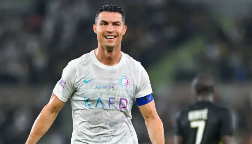 Uśmiechnięty Cristiano Ronaldo w białej koszulce Al Nassr. Ile goli strzelił Ronaldo? To pytanie nurtuje fanów na całym świecie.