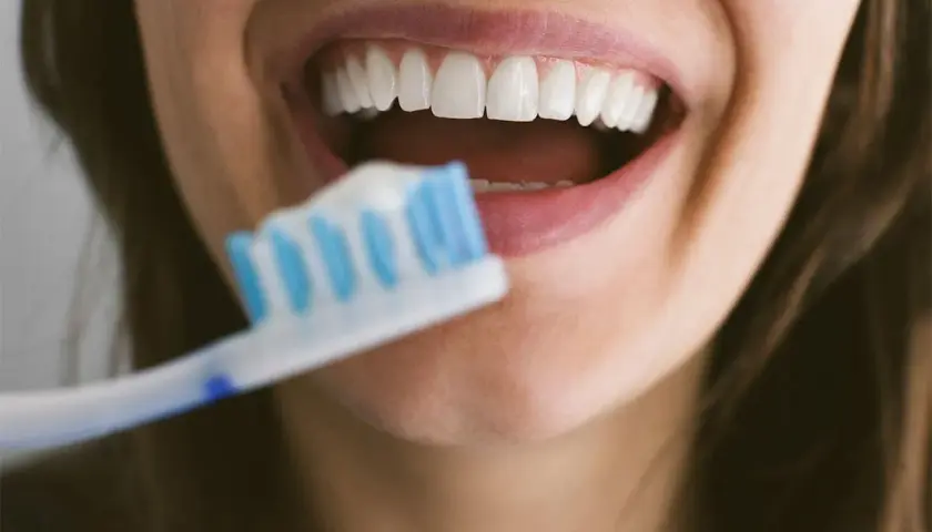 Sorriso smagliante con denti bianchi e spazzolino. Dedicare 10 minuti a lavarsi i denti garantisce un sorriso sano e luminoso.