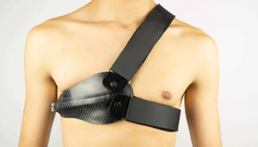 Person mit Carbon-Brustpanzer und Schultergurt. Der Rippenbuckel wird durch die Konstruktion gestützt.