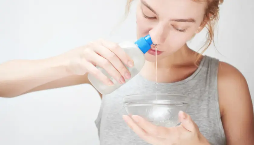 Donna esegue lavaggi nasali con una bottiglietta e una ciotola.