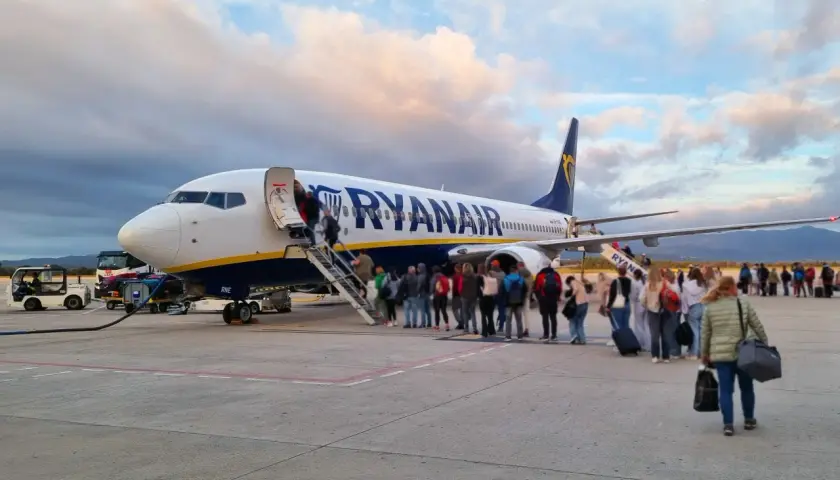 Pasażerowie wsiadają do samolotu Ryanair. W tle chmury i góry. To jak faktura za podróż, która właśnie się zaczyna.