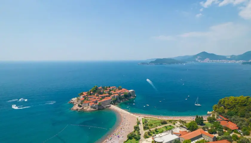 Sveti Stefan, perła czarnogórskiego morza, z malowniczą wyspą połączoną z lądem, otoczona turkusową wodą i zielenią.