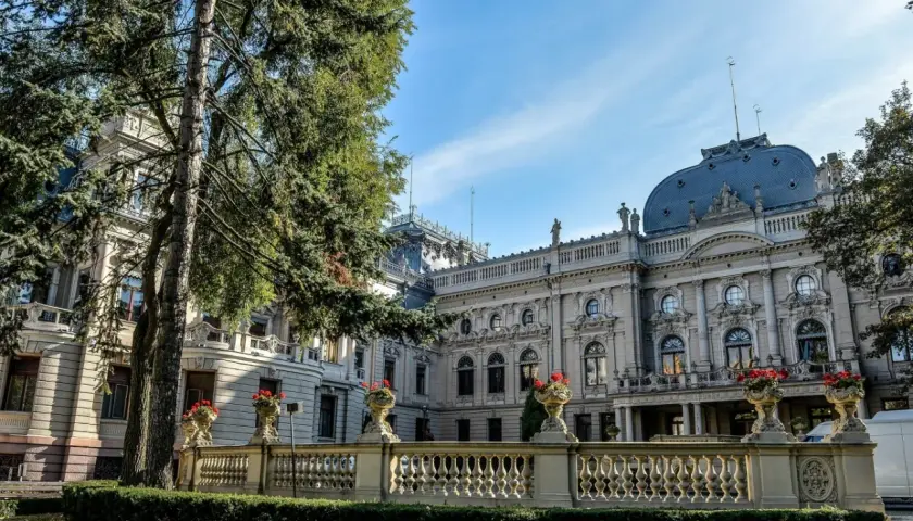 Majestatyczny pałac poznański z ozdobną balustradą i kwitnącymi kwiatami, otoczony zielenią.