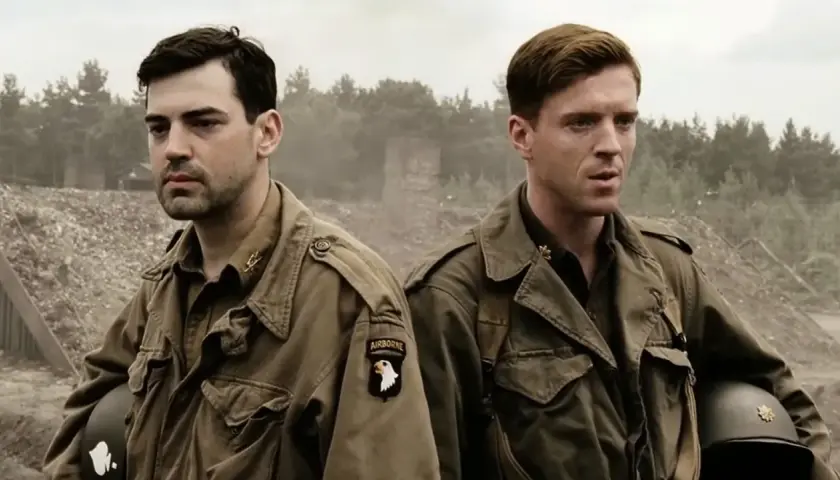 Dwóch żołnierzy w mundurach, symbolizujących bandę braci, stoi na tle zniszczeń. Jeden z nich ma naszywkę "AIRBORNE".