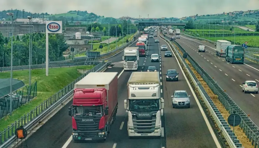 Autostrada pełna ciężarówek, samochodów i znak Esso. To obrazek pokazujący, kabotaż co to jest – transport towarów w obrębie jednego kraju przez zagraniczną firmę.