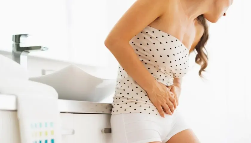 Donna con mani sull'addome, preoccupata per il muco in gravidanza primo trimestre.