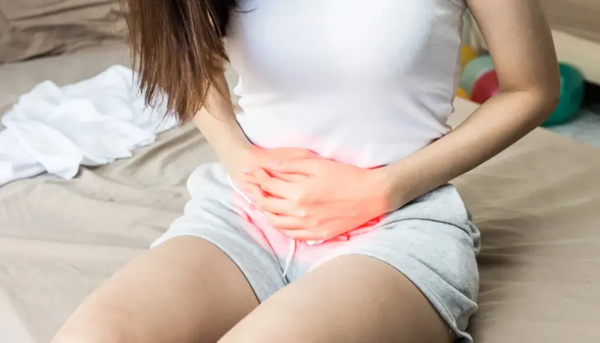 Frau mit Bauchschmerzen, die auf eine Blasenentzündung hindeuten. Osteopathie kann hier Linderung verschaffen, wie positive Erfahrungen zeigen.