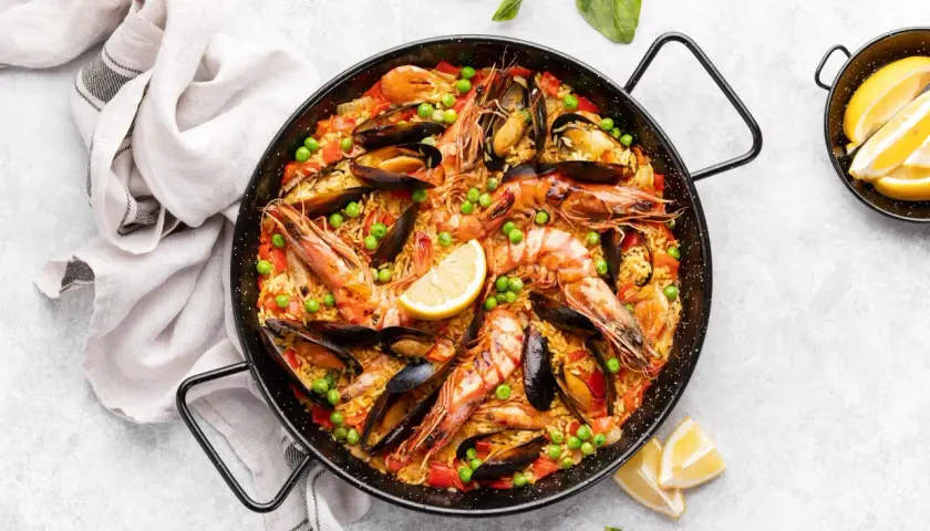 Paella royale aux crevettes et moules, garnie de pois et de citron. Quel vin avec la paella royale ? Un vin blanc sec et fruité, ou un rosé léger.