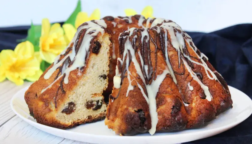 Pyszna babka drożdżowa Ani gotuje, udekorowana lukrem i czekoladą, z rodzynkami w środku.