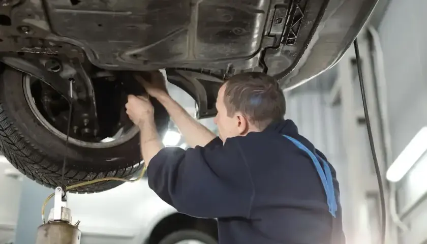 Mechanik wymienia płyn hamulcowy w samochodzie podniesionym na podnośniku.