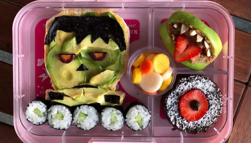 Fun vegan bento ideas! Frankenstein avocado toast, apple monster, sushi, fruit salad, and a chocolate cake.