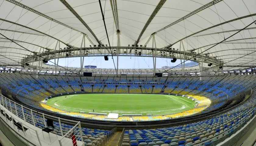 Pusta Marakana, stadion w Rio de Janeiro, z zieloną murawą i niebiesko-żółtymi trybunami pod białym dachem.