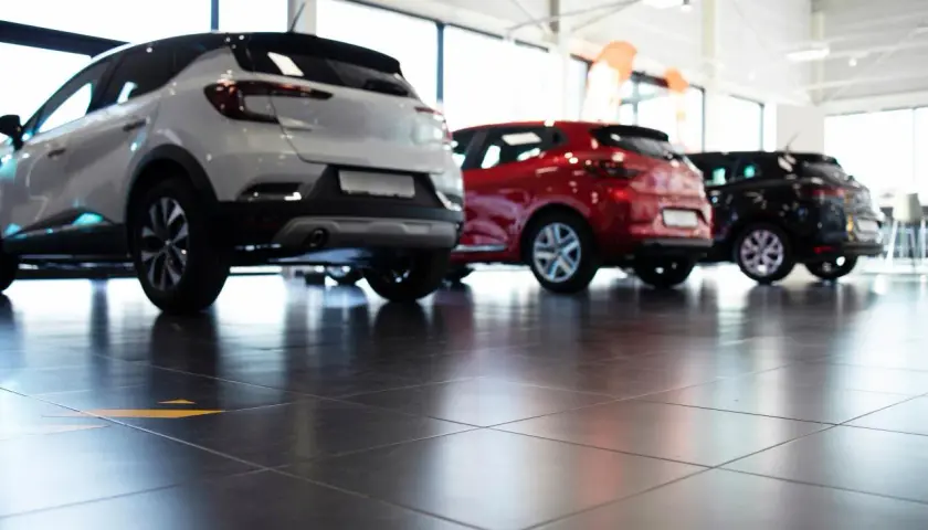 Tre auto, bianca, rossa e nera, in un concessionario. La valutazione autoscout è facilitata dalla vista posteriore dei veicoli.