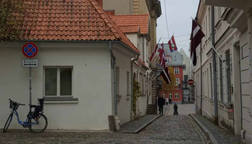 Urokliwa uliczka w Rydze, z brukowaną nawierzchnią, domami z czerwonymi dachami i łopoczącymi flagami Łotwy. Idealne miejsce, by poczuć atmosferę miasta i odkryć, co zobaczyć w Rydze.