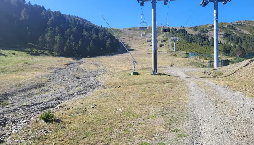 Remontes mecánicos en una ladera verde y rocosa, con la torreta de l orri como punto de referencia.