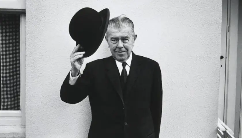Hombre con bombín saluda, como en un espejo de Magritte.