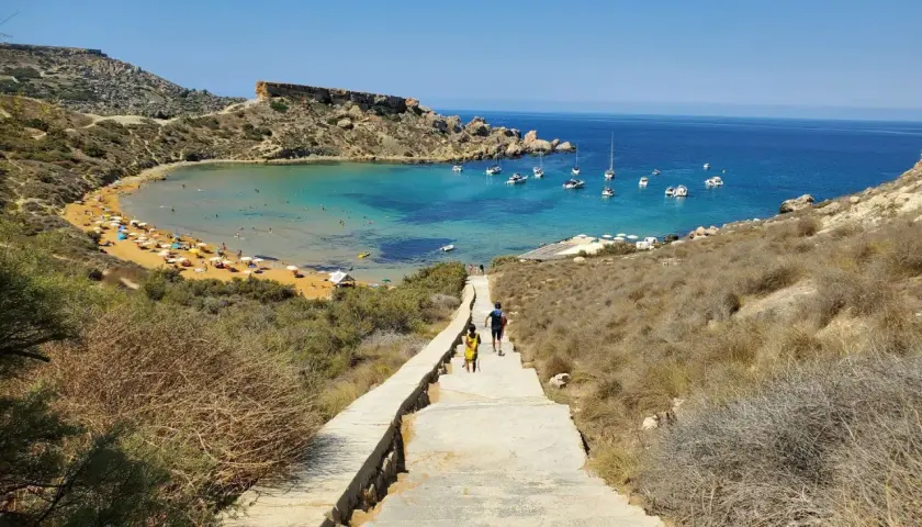 Malta, kwiecień: słoneczna pogoda zachęca do spaceru schodami w dół do zatoki z turkusową wodą i łodziami.