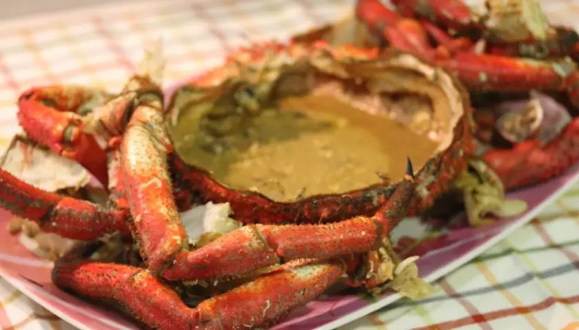 Centolla cocida con sus huevas, lista para disfrutar. Sus patas rojas y su caparazón lleno de sabor la hacen irresistible.